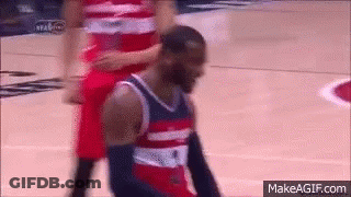 A Basketball Player Is Kneeling Down On The Court While Another Player Stands Behind Him GIF