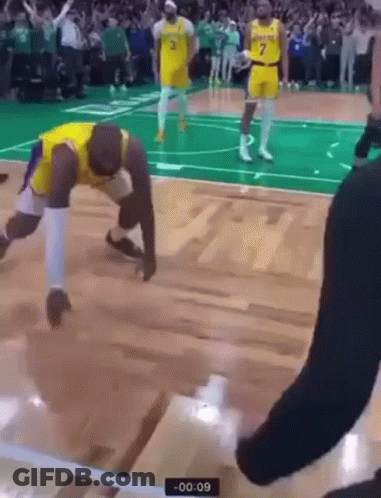 A Basketball Player Is Kneeling On The Floor During A Game While A Referee Watches . GIF