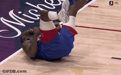 A Basketball Player Is Laying On His Back On A Court With Michigan Written On It GIF