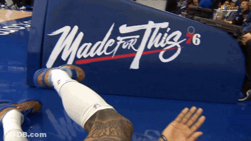 A Basketball Player Is Laying On The Floor In Front Of A Banner That Says Made For This GIF