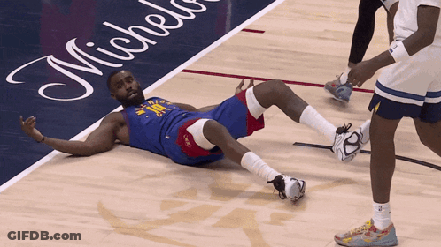 A Basketball Player Is Laying On The Floor In Front Of A Michelin Advertisement GIF