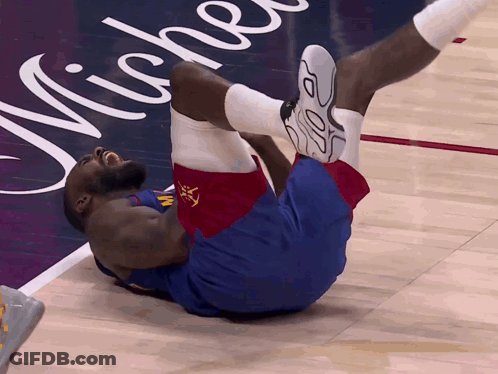 A Basketball Player Is Laying On The Floor In Front Of A Michelle Advertisement GIF