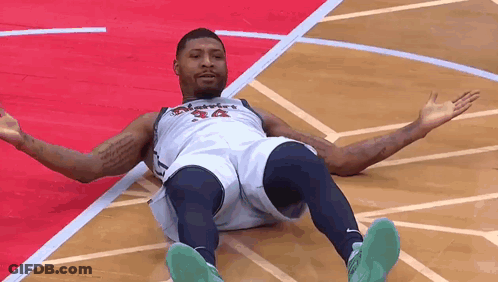 A Basketball Player Is Laying On The Floor Of A Basketball Court . GIF