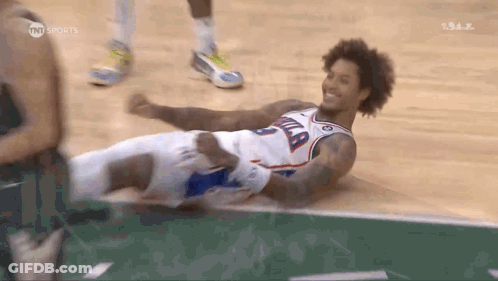 A Basketball Player Is Laying On The Floor With His Legs Crossed And Smiling . GIF