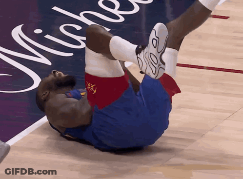 A Basketball Player Is Laying On The Floor With His Legs Up GIF