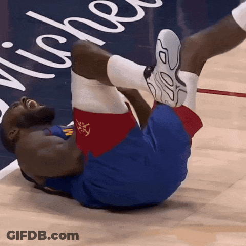 A Basketball Player Is Laying On The Floor With His Legs Up In Front Of A Sign That Says Niche GIF