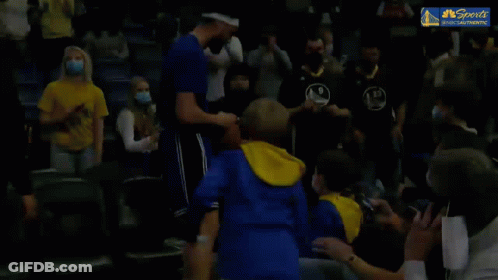 A Basketball Player Is Shaking Hands With A Young Boy In The Stands During A Game . GIF