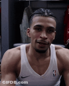 A Basketball Player Is Sitting In A Chair In A Locker Room Wearing A White Nike Tank Top . GIF