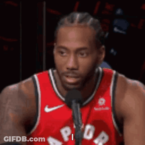 A Basketball Player Is Sitting In Front Of A Microphone . GIF