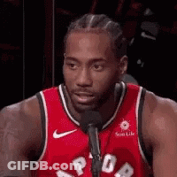 A Basketball Player Is Sitting In Front Of A Microphone . GIF