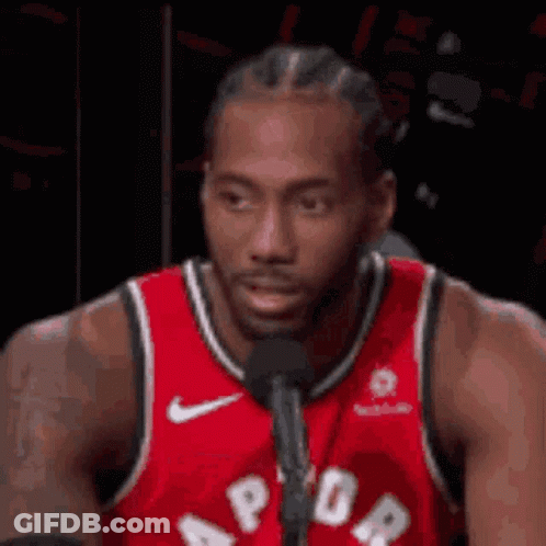 A Basketball Player Is Sitting In Front Of A Microphone . GIF