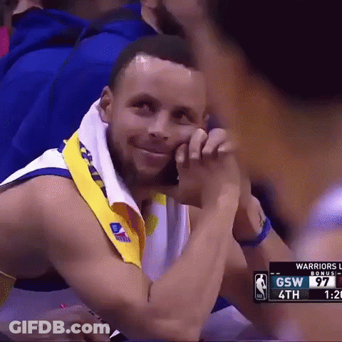 A Basketball Player Is Sitting In The Stands With A Towel Around His Neck And Smiling . GIF