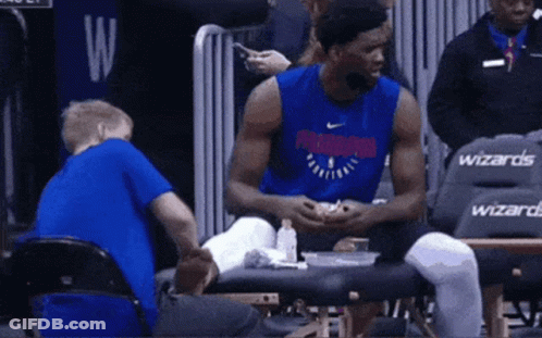 A Basketball Player Is Sitting On A Bench Talking To A Child . GIF