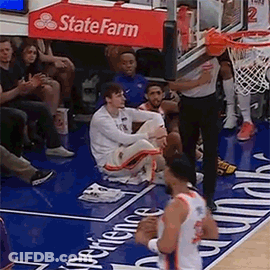 A Basketball Player Is Sitting On The Floor During A Game While A Referee Looks On . GIF