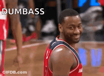 A Basketball Player Is Smiling And Looking At The Camera While Standing On A Basketball Court . GIF