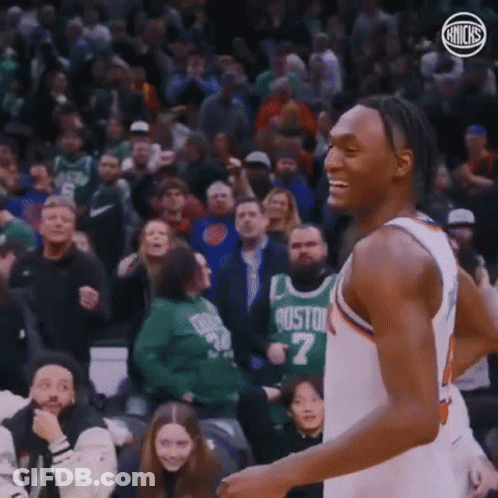 A Basketball Player Is Smiling While Standing In Front Of A Crowd At A Basketball Game . GIF