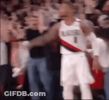 A Basketball Player Is Standing In Front Of A Crowd Of Fans . GIF