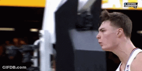 A Basketball Player Is Standing In Front Of A Screen That Says National Championship . GIF