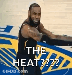 A Basketball Player Is Standing On A Court With His Arms Outstretched And Says `` The Heat '' . GIF