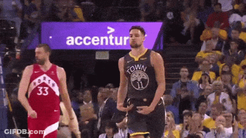 A Basketball Player Is Standing On The Court In Front Of A Crowd While Another Player Stands Behind Him . GIF