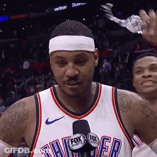 A Basketball Player Is Talking Into A Microphone While Wearing A Headband And Holding A Bottle Of Water . GIF