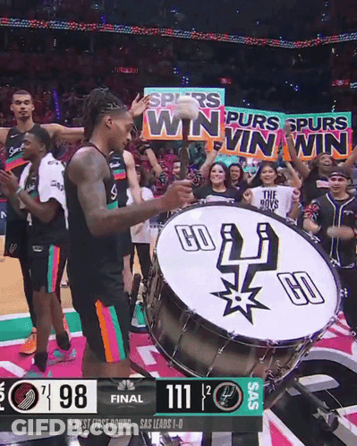 A Basketball Player Playing A Drum With A Banner That Says " Spurs Win Win Win " GIF
