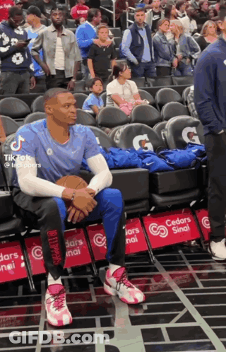 A Basketball Player Sits In The Stands With A Gatorade Advertisement On The Seats GIF