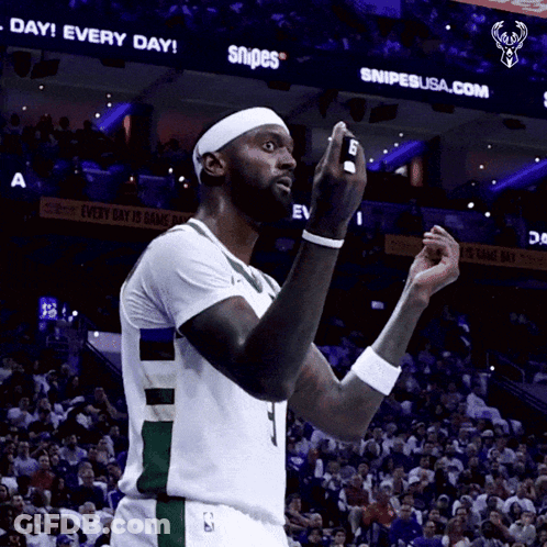 A Basketball Player Stands In Front Of A Sign That Says Snipes On It GIF