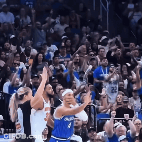 A Basketball Player Wearing A Blue Orlando Jersey Stands In Front Of A Crowd GIF