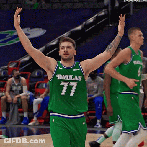 A Basketball Player Wearing A Dallas 77 Jersey Is Raising His Arms In The Air GIF