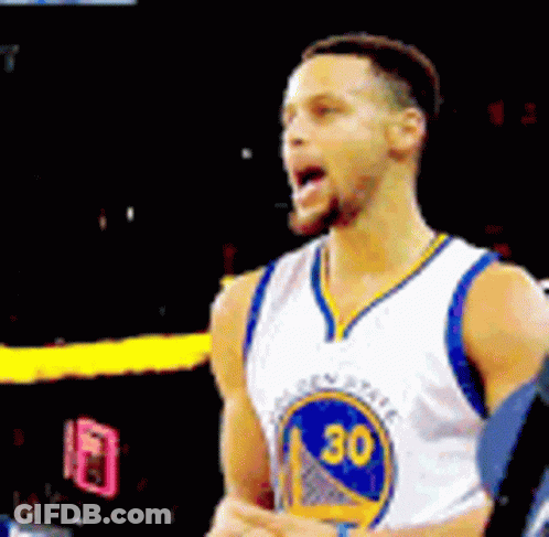 A Basketball Player Wearing A Golden State Warriors Jersey Is Standing On A Court With His Tongue Out . GIF