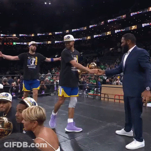 A Basketball Player Wearing A Golden State Warriors Shirt Shakes Hands With A Man In A Suit GIF