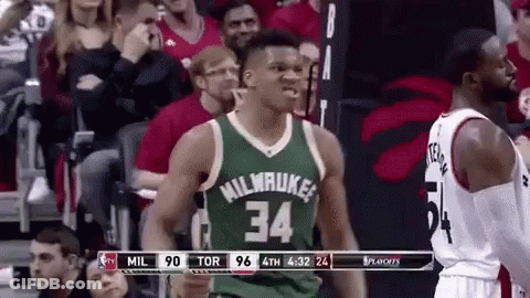 A Basketball Player Wearing A Green Jersey With The Number 34 On It Is Standing In Front Of A Crowd Of People . GIF