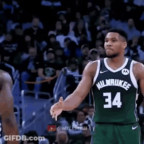 A Basketball Player Wearing A Green Jersey With The Number 34 On It Is Talking To Another Player On The Court . GIF