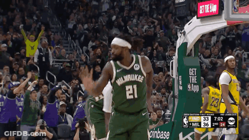 A Basketball Player Wearing A Green Milwaukee Jersey Stands In Front Of A Crowd GIF