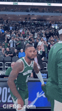 A Basketball Player Wearing A Green Milwaukee Jersey Stands On The Court GIF