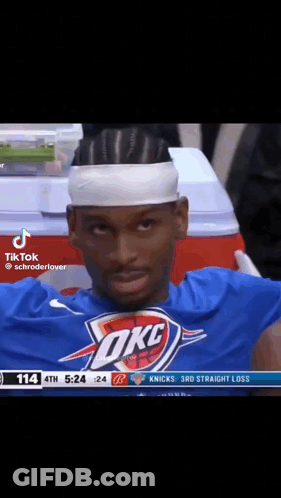 A Basketball Player Wearing A Headband And A Okc Shirt Is Sitting In The Stands During A Game . GIF