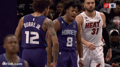 A Basketball Player Wearing A Hornets Jersey Stands Next To A Player Wearing A Heat Jersey GIF