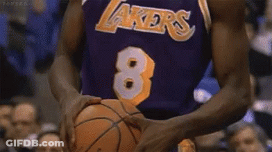 A Basketball Player Wearing A Lakers Jersey Is Holding A Basketball In His Hands . GIF
