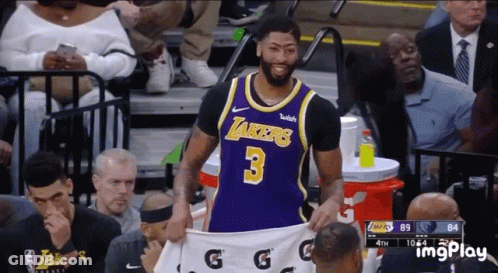 A Basketball Player Wearing A Lakers Jersey Is Holding A White Gatorade Shirt GIF