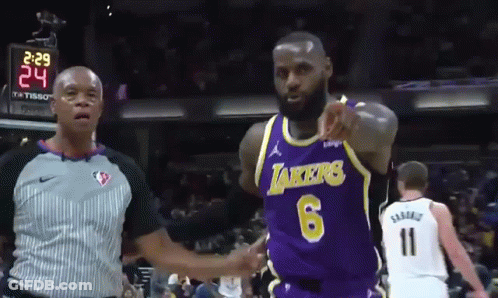 A Basketball Player Wearing A Lakers Jersey Is Pointing At A Referee GIF