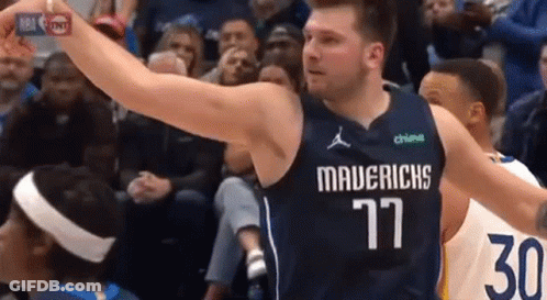 A Basketball Player Wearing A Mavericks Jersey Is Holding A Basketball In His Hand . GIF
