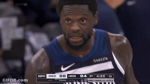 A Basketball Player Wearing A Minnesota Jersey Stands In The Stands GIF