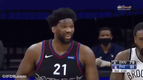 A Basketball Player Wearing A Number 21 Jersey Is Laughing While Standing Next To Another Player . GIF