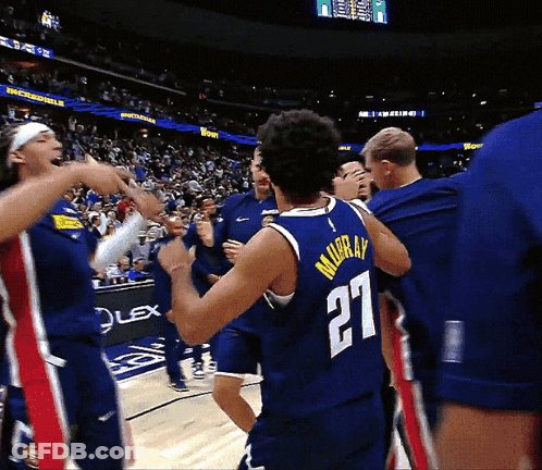 A Basketball Player Wearing A Number 27 Jersey Is Surrounded By His Teammates GIF