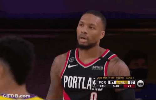 A Basketball Player Wearing A Portland Jersey Stands In Front Of A Referee GIF