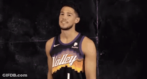 A Basketball Player Wearing A Purple And Black Jersey Is Smiling . GIF