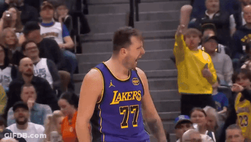 A Basketball Player Wearing A Purple Lakers Jersey Celebrates In Front Of A Crowd GIF