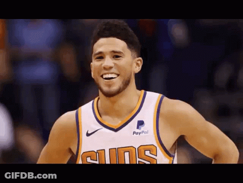 A Basketball Player Wearing A Suns Jersey Is Smiling . GIF