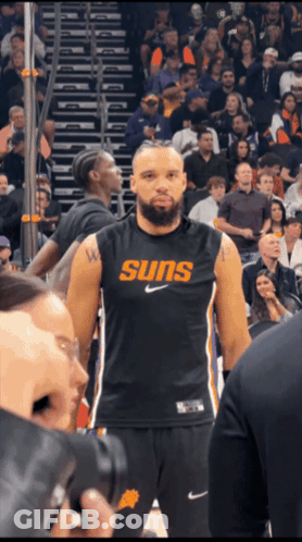 A Basketball Player Wearing A Suns Jersey Stands In Front Of A Crowd GIF